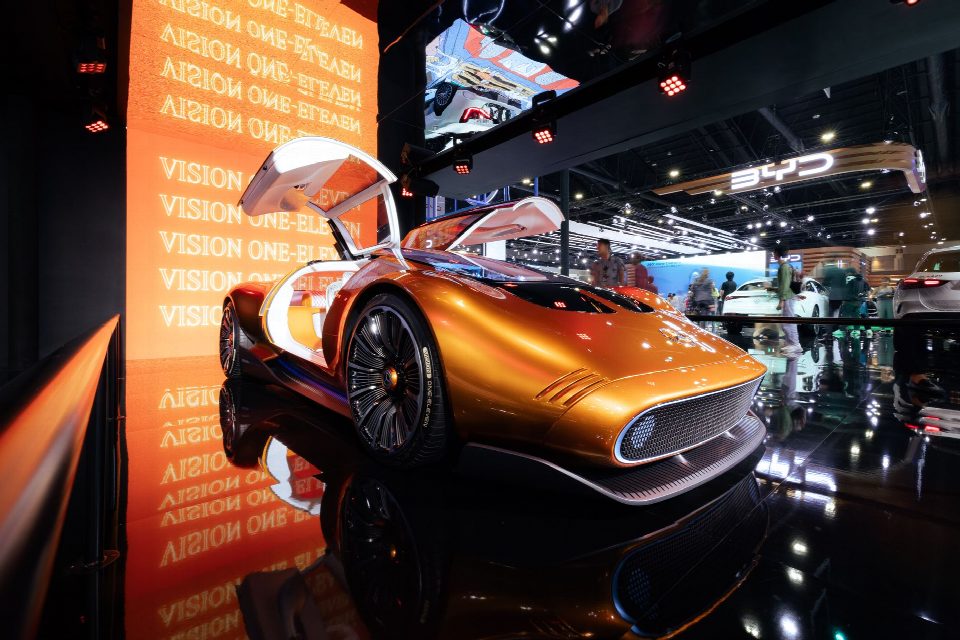 A sleek futuristic concept car in vivid orange displayed at an international motor show. A sleek futuristic concept car in vivid orange displayed at an international motor show.