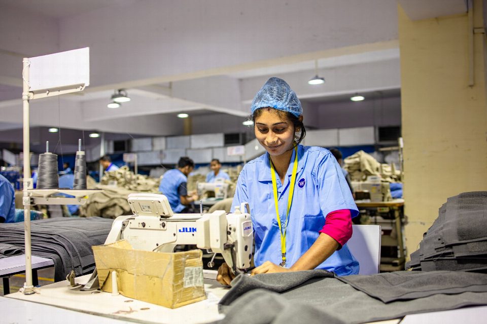 A female textile worker sewing fabric in an industrial factory setting. A female textile worker sewing fabric in an industrial factory setting.